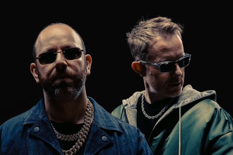 Portrait of electronic music duo Chase & Status wearing sunglasses against a dark background.